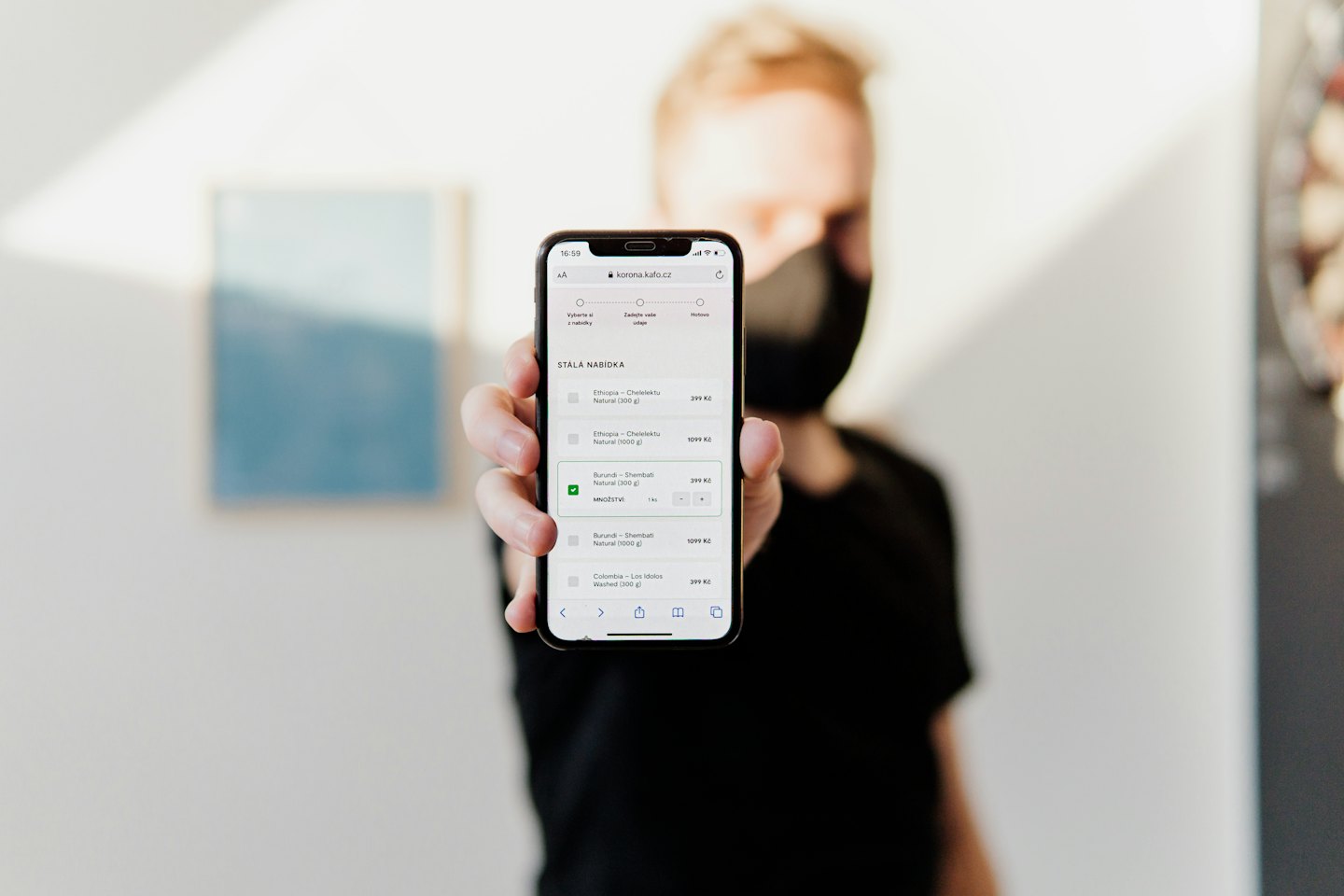 Eine Person hält ein Smartphone mit einer Kaffee-E-Commerce-Website.